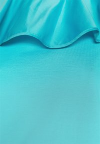 Tela turquesa con una textura suave, que presenta un borde ondulado en la parte superior y un fondo sólido en la parte inferior, ideal para ropa casual.