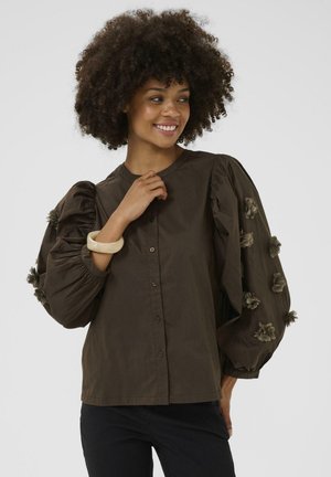 Brown blouse with large, puffed sleeves and floral embellishments. It features a button-down front and a round neckline.