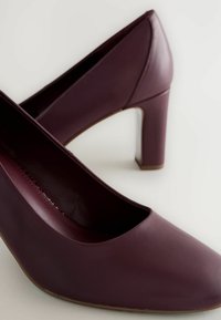 Burgundy korkokengät, joissa on sileä nahkapinta, pyöreä kärki ja keskipitkä lohkokanta, sekä matala leikkaus muotoilu.