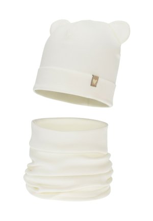 White knitted beanie with bear ears and a small heart tag. Matching white neck gaiter designed with a smooth, stretchy fabric.