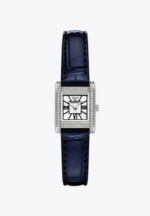 Rechteckige Armbanduhr aus Edelstahl mit einem Zifferblatt aus weißem Perlmutt und schwarzen geometrischen Markierungen, umrahmt von einer Reihe klarer Kristalle, und einem navyblauen Lederband.