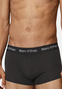 Schwarze Baumwollslips mit körperbetontem Design, ausgestattet mit einem elastischen Logo-Bund mit "Marc O’Polo"-Schriftzug und glatter Textur.