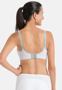Lichtgrijze sportbh met een gestructureerd meshontwerp. Beschikt over verstelbare sp straps en een haak-en-oogsluiting op de rug.