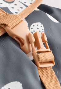 Gray fabric featuring a pattern with white and black elements, complemented by a beige plastic buckle and woven strap.