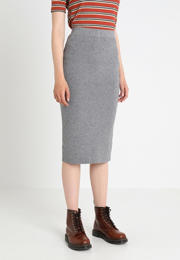 Šedá vlněná tužková sukně s vysokým pasem a přiléhavým střihem, oblečená s hnědými šněrovacími kotníkovými botami a pruhovaným tričkem.