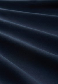 Tessuto blu scuro con pieghe orizzontali lisce e uniformemente distanziate che creano morbide ombre e riflessi.