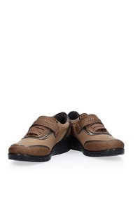 Zapatos de cuero marrón con un acabado suave y detalles de costura. Cuentan con una correa de Velcro, una plantilla acolchada y una suela de goma para mayor tracción.