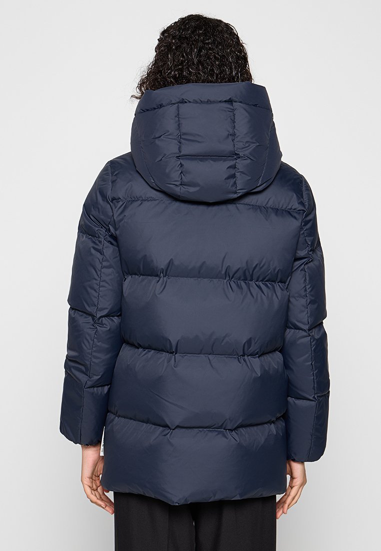 Granatowa kurtka puchowa z kapturem, z pikowanym wzorem i wyściółką. Tył ma poziome szwy i luźny krój.