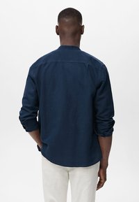 Tummansininen pitkähihainen paita, jossa on pyöristetty helma, käännetyt hihat ja rento istuvuus, valmistettu kevyestä materiaalista. Takaviisto esitetty.