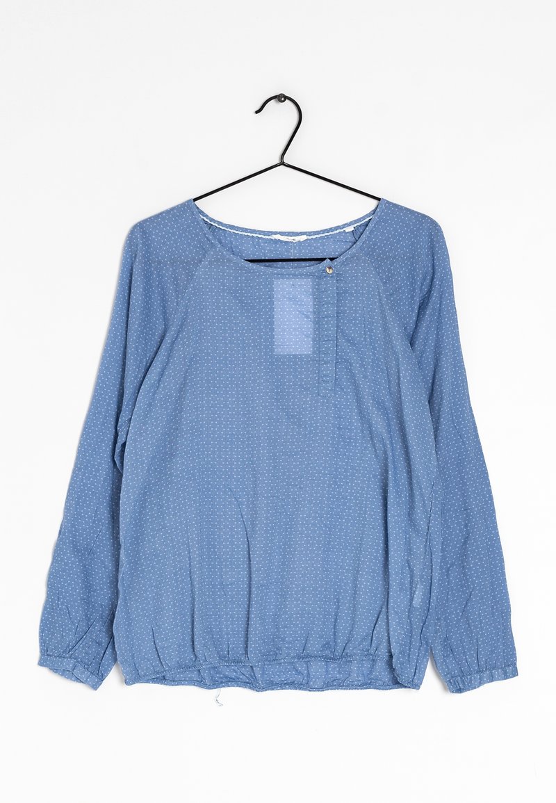 Camicia a maniche lunghe azzurro chiaro in tessuto con pois bianchi, con scollatura tonda e orlo elasticizzato. Dettaglio di piccolo bottone sul davanti.