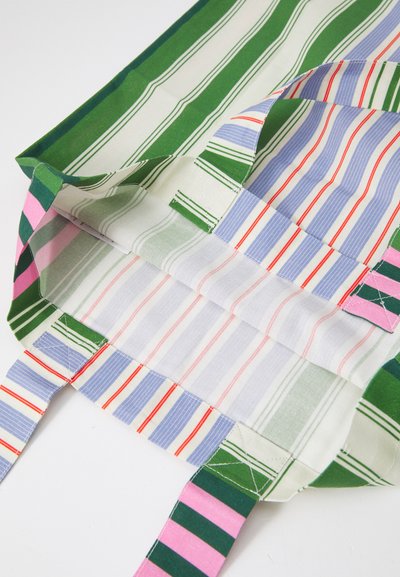 Mångmönstrad tygväska med gröna och rosa randiga handtag; insidan har växelvis blå och vita randiga mönster.