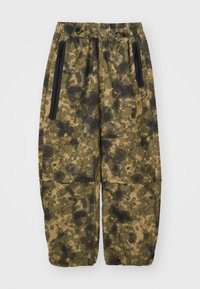 Camouflage cargo pants in shades of green and brown, made of textured fabric. Features side zip pockets and an elastic waistband.