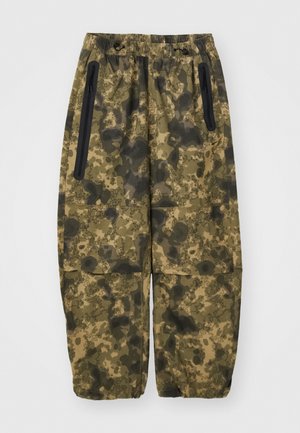 Pantalons cargo camouflage dans des nuances de vert et de marron, fabriqués en tissu texturé. Possède des poches latérales avec fermeture éclair et une taille élastique.