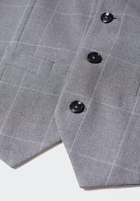 Gilet de costume à carreaux gris avec des boutons noirs et une poche passepoilée sur fond blanc.