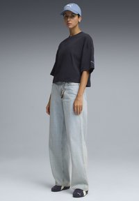 Marine cropped t-shirt, lyseblå baggy jeans, blå baseball cap, sorte slip-on sko. Nøglering fastgjort i taljen.