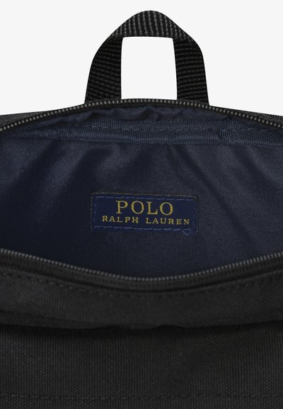 Wnętrze czarnej torby z tkaniny z niebieską podszewką, wyposażone w przyszytą metkę z napisem "POLO RALPH LAUREN" w złotym kolorze. Zapięcie na zamek.