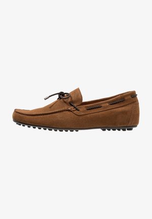 Mocassin en daim marron avec lacet tressé noir noué en nœud, détails cousus et semelle en caoutchouc avec crampons antidérapants.