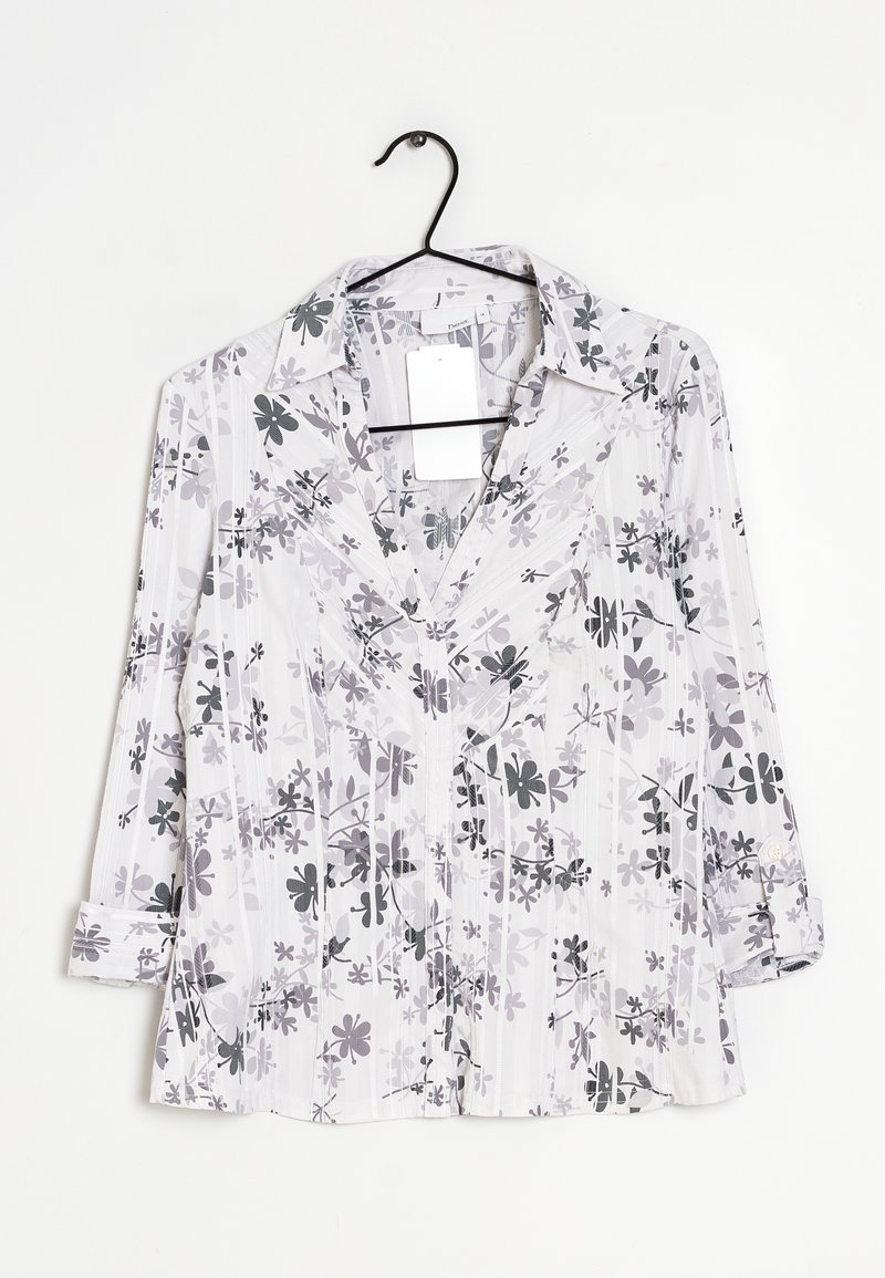 Chemise à manches longues avec un col en V, en tissu blanc présentant un motif floral gris et des rayures subtiles, détail de boutons sur les poignets retroussés.