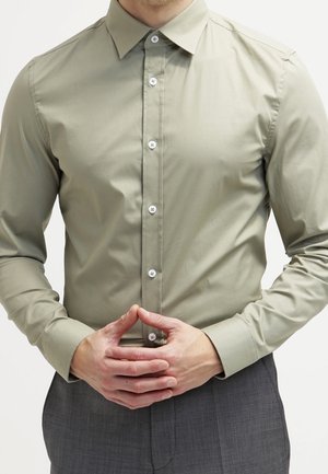 Lichtgroene button-up blouse van gladde stof, met een klassieke kraag en een eenvoudig ontwerp, voorzien van contrasterende knopen en manchetten.