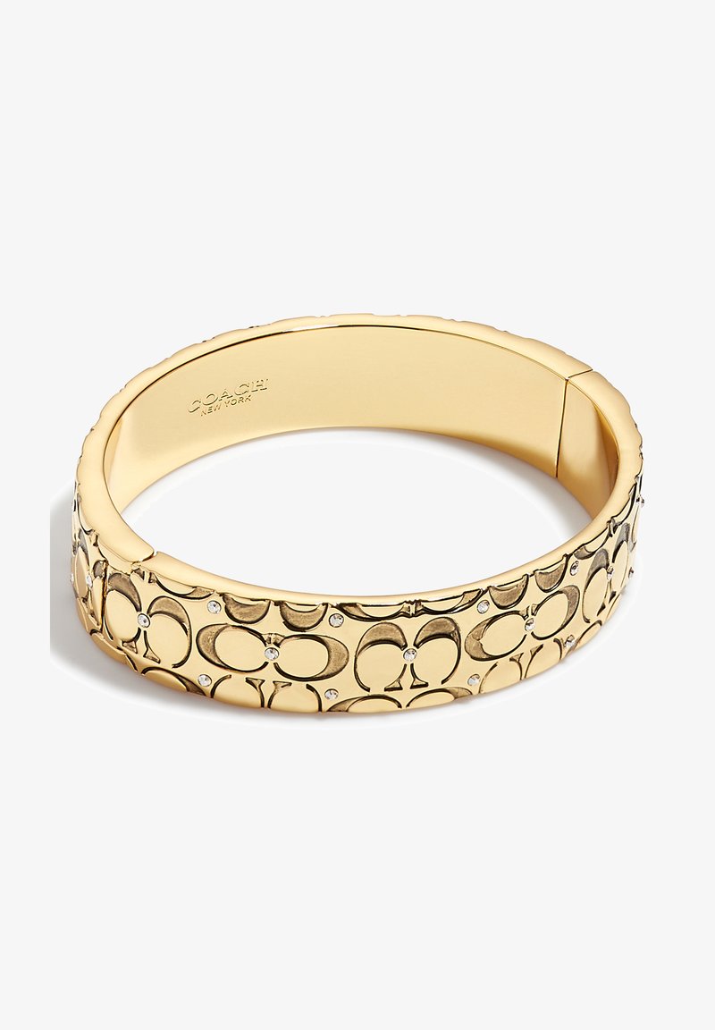 Bracelet jonc doré avec motif logo Coach embossé et petits accents de cristal, intérieur poli estampillé Coach New York.