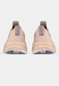 Chaussures de sport rose clair avec tige texturée, languette de talon rembourrée et semelle en caoutchouc multicolore avec accents verts et bleus.