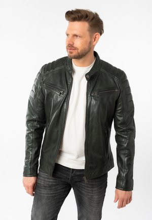 Dunkelgrüne Leder-Motorradjacke mit gerippten Schulterdetails, Reißverschlusstaschen und Stehkragen, getragen über einem weißen Hemd.