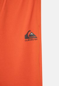 Orange Quiksilver-shorts i ett mjukt material med en liten logotyp på nedre vänstra sidan. Enkelt design med resårlinning.