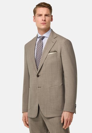 Beige Anzugjacke aus strukturiertem Stoff. Einreiher-Design, zwei Fronttaschen und ein kontrastierendes Taschentuch. Hellblau gestreiftes Hemd.