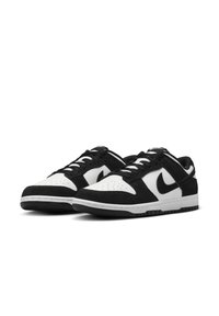 Čierno-biele Nike tenisky s vrchnou časťou z semišu, perforovanou špičkou, šnúrkami a gumovou podrážkou s výrazným logom na boku.