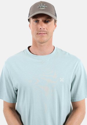 Homme portant un t-shirt bleu clair et une casquette de baseball grise avec un logo de bateau de pêche et des rames, faisant face à l'avant sur un fond blanc.