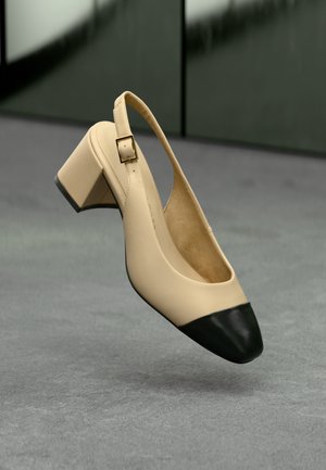 Pantofi slingback din piele bej cu vârf negru, toc mic, de bloc și detaliu cu cataramă pătrată aurie. Textură netedă, design minimalist.