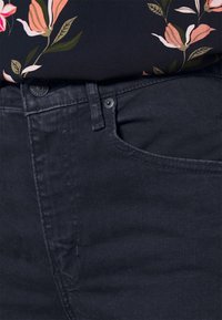 Jeans azul oscuro con un diseño clásico de cinco bolsillos, textura suave y detalles de costura sutil a lo largo de las costuras y los bolsillos.