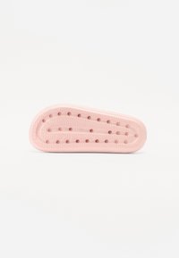 Pink shoe insole with textured surface, rounded shape, drainage holes, and light cushioning. Designed for comfort and breathability.