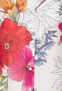 Tejido con un patrón floral que presenta grandes flores rojas, rosas y azules sobre un fondo blanco. Incluye botones blancos a lo largo del centro.