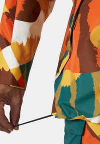 Bunte, gemusterte Jacke mit orangefarbenen, braunen, grünen und gelben Abschnitten; verfügt über einen Kordel-Detail und ein strukturiertes Gewebe.