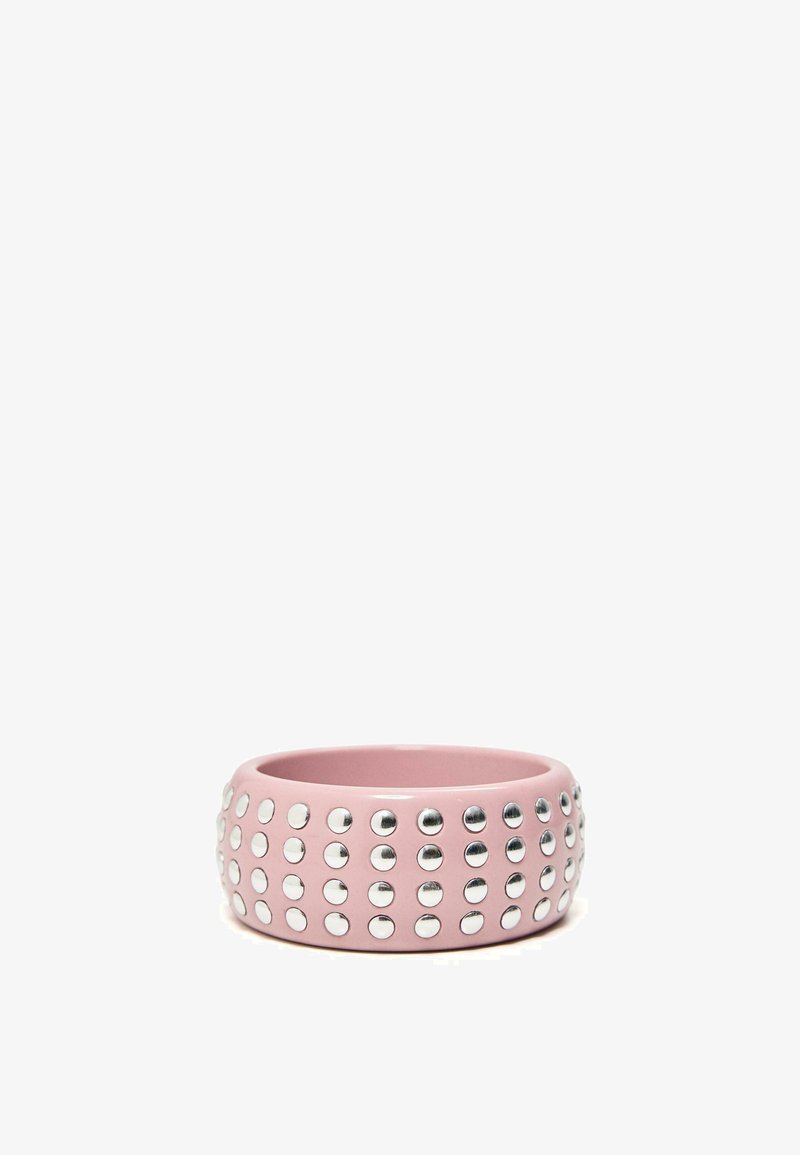 Large bracelet jonc rose orné de quatre rangées de clous argentés espacés uniformément autour de sa circonférence.