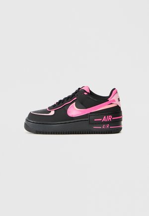 Czarny niskoprofilowy sneaker Nike z jaskraworóżowymi akcentami, logo Swoosh i oznaczeniem "AIR" na grubej podeszwie, na jednolitym jasnym tle.