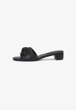 Sandali in pelle nera con tacco basso e a blocco. Presentano un design incrociato sulla cinghia e una superficie testurizzata. Accentuati da un dettaglio decorativo.