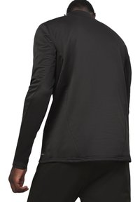 Schwarzes, athletisches Langarmoberteil mit glatter Textur, hochgeschlossen und tailliert, von hinten mit sauberem Saum gezeigt.