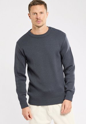 Pull en maille gris foncé avec un col rond, des bords-côtes aux poignets et à l'ourlet, présentant des boutons décoratifs à l'épaule.