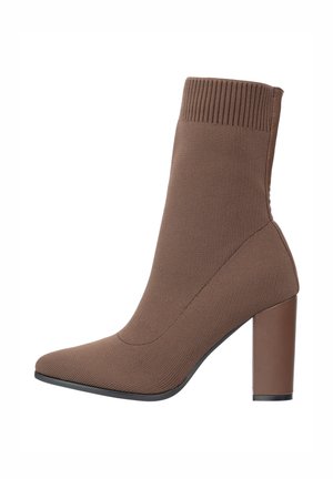 Bottine en maille marron avec un bord-côte, un bout pointu et une semelle à talon épais, présentant une finition lisse et un design élégant et épuré.