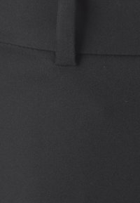 Zwarte stof met een gladde textuur, met een subtiele glans. Perfecte pasvorm met een nette naad en een kleine tailleband. Geen zichtbare patronen.