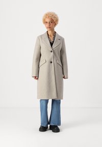 Cappotto grigio chiaro in misto lana con rever a punte, chiusura con un solo bottone, due tasche laterali e una silhouette leggermente svasata.