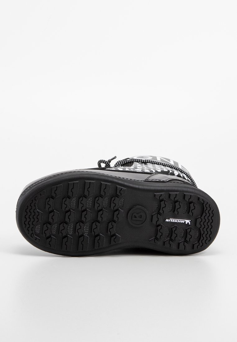 Schwarzer Gummistiefel mit strukturiertem Profil, der tiefe Rillen und ein geformtes Design aufweist. Enthält metallische Akzente und gemusterte Schnürsenkel.