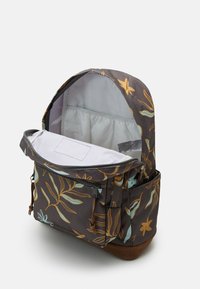 Sac à dos en tissu gris foncé avec un motif floral jaune et bleu clair. Équipé d'un compartiment principal zippé et de poches latérales.