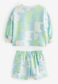 To-delt sæt bestående af en crop top og shorts. Materialet er i pastelfarver som blå, grøn og hvid med store blomster mønstre og en påsyet lomme på shorts.