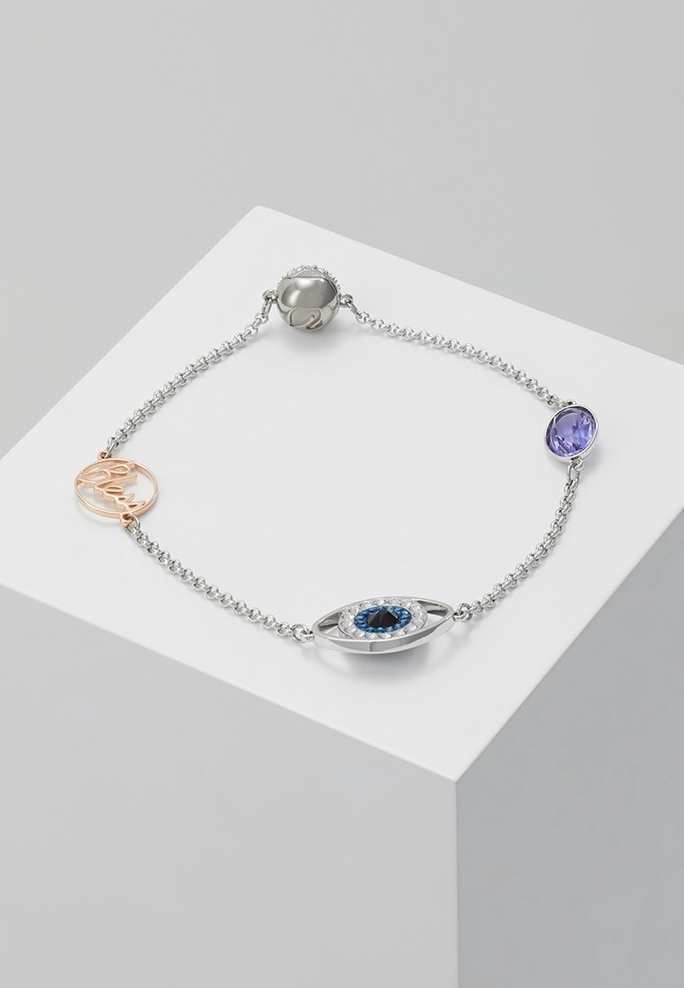 Bracelet chaîne en argent avec un pendentif œil bleu en cristal, une pierre précieuse ovale violette, un fermoir rond en argent et une petite étiquette circulaire en or rose.