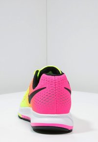 Běžecká obuv Nike s horní částí z růžové a žluté síťoviny, černými akcenty a texturovanou podrážkou. Obsahuje těsný límec na patě a prodyšný materiál.