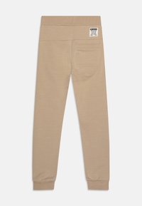 Beige Jogginghosen mit glatter Textur, elastischem Bund, gerippten Bündchen und einer Gesäßtasche mit einem dezenten Etikett.