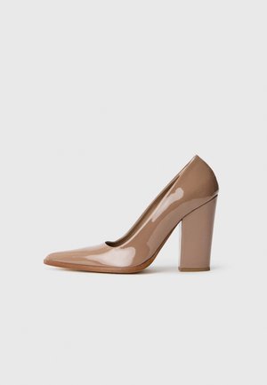 Beige patent leather high heel pump with a pointed toe and a chunky square heel. Smooth texture with a glossy finish.